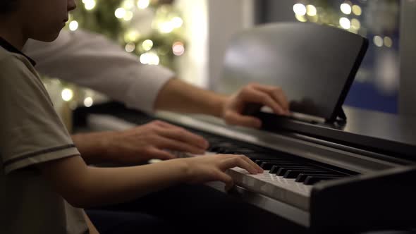 A music teacher gives a child piano lessons. Playing a musical instrument.