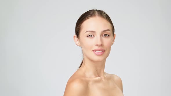 Beautiful Young Woman with Clean Fresh Skin Standing Over Light Grey Background