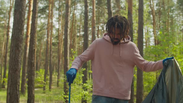 Male Charity Volunteer Picking Up Litter in Forest