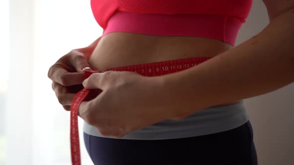 Close Up of a Pregnant Woman in a Tracksuit Measuring the Circumference of Her Tummy with a Tape