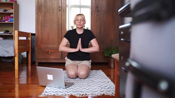 Middle Age Woman Mediating and Doing Yoga at Home with Laptop Online Class