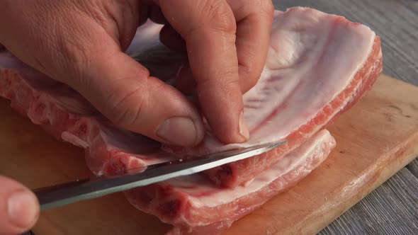 Closeup of the Male Hands Cutting Off the Fatty Film From the Raw Ribs