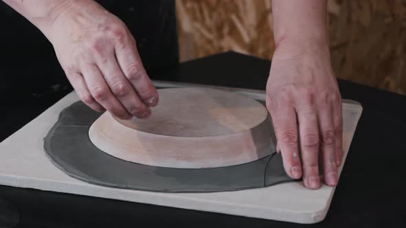 Pottery  a Woman Cuts Off a Piece of Rolled Clay By the Sample of a Plate