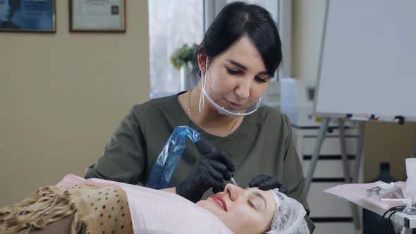 Cosmetologist Applies Permanent Makeup to Eyebrows in a Beauty Salon