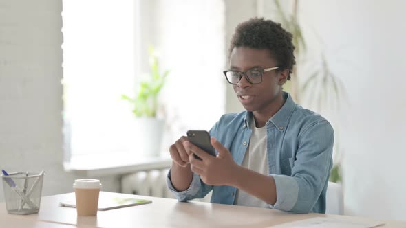 Successful Young African Man Celebrating on Smartphone