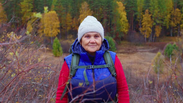 Aged Woman in Warm Clothes Standing in Forest