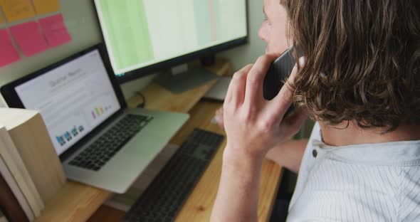 Focused caucasian man working remotely, using laptop and talking on smartphone