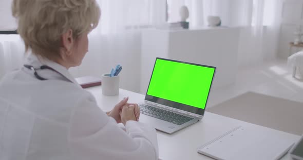 Woman Physician Is Listening Patient During Online Consultation, Looking at Green Screen of Laptop