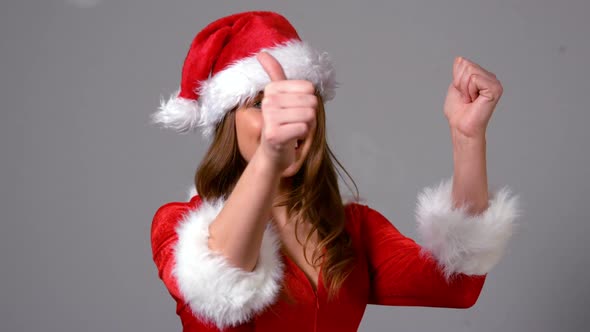 Cute girl in santa costume turning to camera with thumbs up