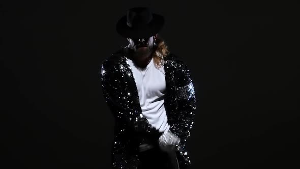 Young Stylish Man Dancing in Style Michael Jackson, Spotlight on a Black Background