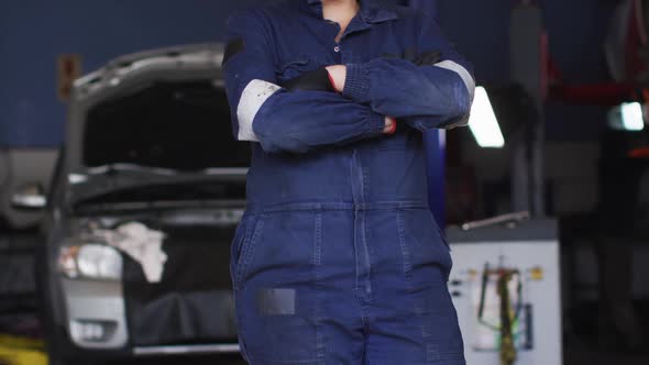 Portrait of female mechanic with arms crossed smiling at a car service station