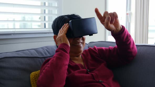 Senior woman using virtual reality headset in living room