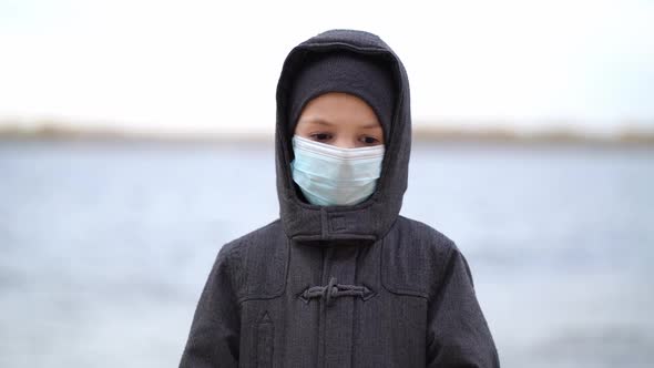 Boy Medical Mask on His Face During Quarantine Stands on Beach During the Second Wave Quarantine