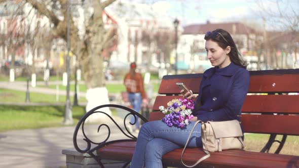 Cute Girl in the Spring Park Enjoys the Phone Smiling