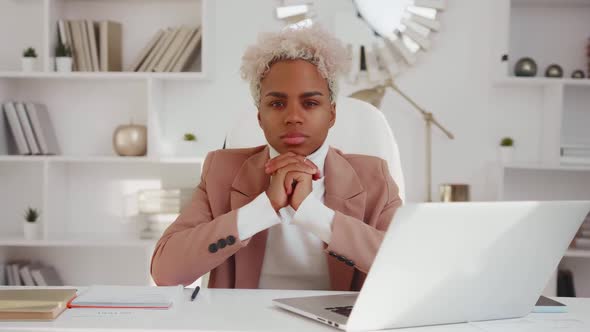 Young African American Woman Tutor Looks at Camera Sits at Office with Laptop