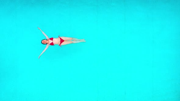 View From the Top As a Woman in a Red Swimsuit Lying on Her Back in the Pool