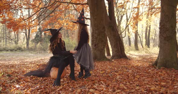 Beautiful Brunette Mom and Cute Little Daughter Looking Like Witches in Special Dresses and Hats in