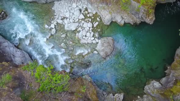 Aerial top down dolly out of Rio Azul stream flowing between rocky cliffs surrounded by vegetation,