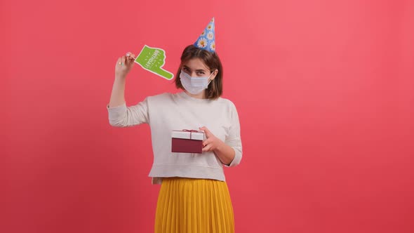 Woman with Medical Mask on Face Showing with a Cardboard Finger at the Gift Box.