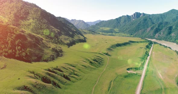 Aerial Rural Mountain Road and Meadow at Sunny Summer Morning. Asphalt Highway and River