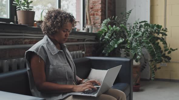 Woman Using Laptop on Sofa in Office