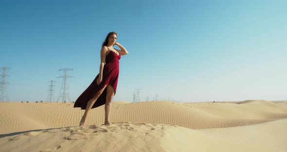 Athletic Flexible Woman in Red Dress is Dancing and Doing Gymnastics in Desert
