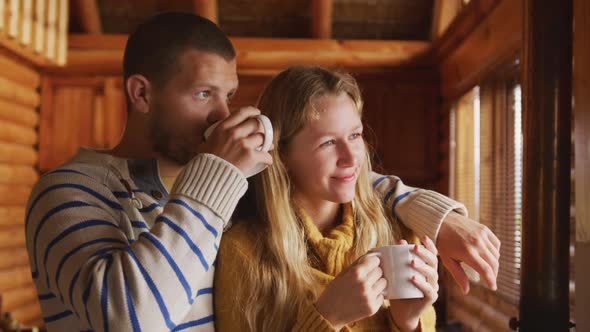 Caucasian couple spending time at home together, looking at the window, drinking beverage