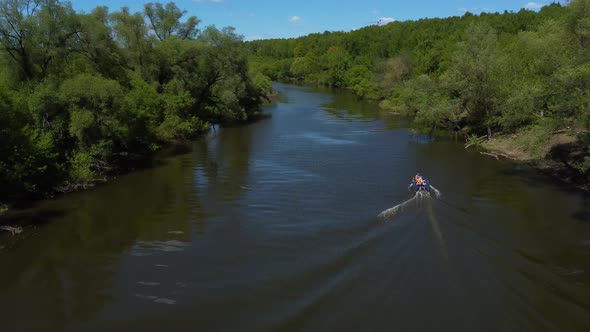 Rescue Boat with People in Orange Vests on Board Floats on the Narrow River