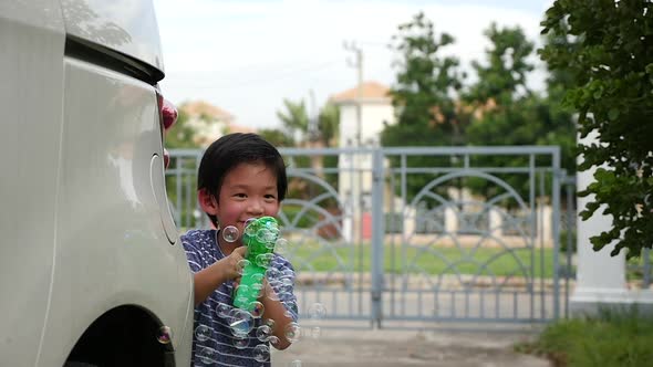 Cute Asian Child Shooting Bubbles From Bubble Gun Behind A Car Slow Motion