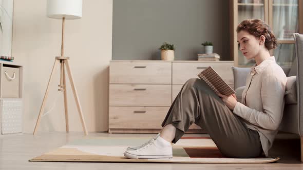 Woman Reading Book Sitting on Floor