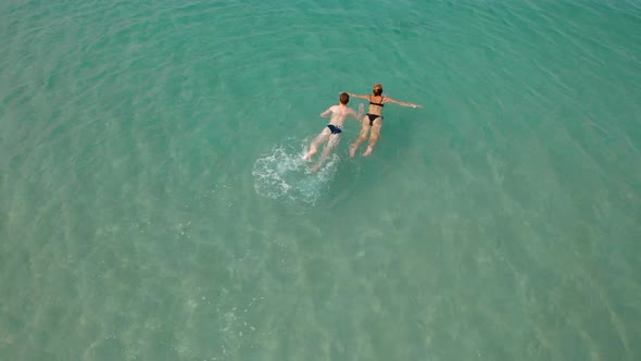 A Young Mother with Her Teenage Son are Swimming in a Tropical Blue Sea with Waves Aerial Footage