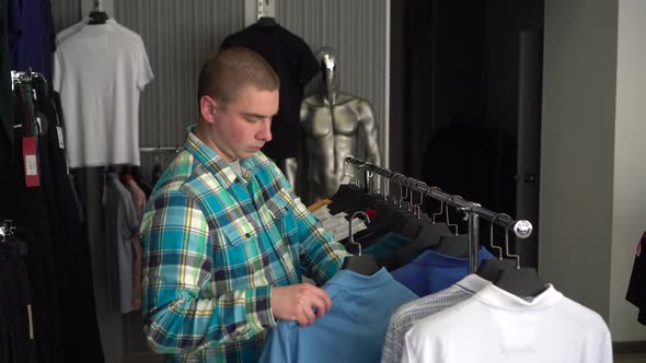 A Young Man Chooses a Shirt in a Store and Is Surprised at the Expensive Price of a Shirt. Clothing