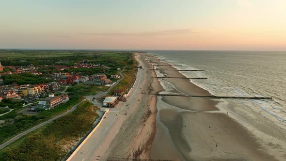 Spectacular aerial orbit shot of an endless beach and a picturesque little coastal town with orange