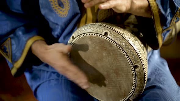 Tight shot of man in Moroccan dress playing arabic doumbek, darbuka, or derbeki