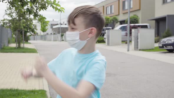 A Young Boy Puts on a Face Mask and Dances in an Empty Suburban Area