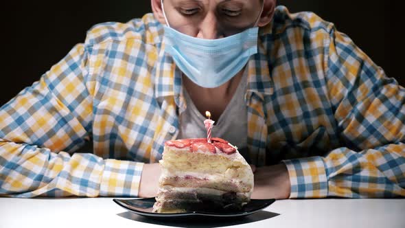 Man in Blue Disposable Mask Blows Burning Fire on Candle