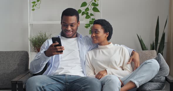 Loving Afro American Ethnic Couple Sitting on Sofa at Home Talking Spending Time Together at