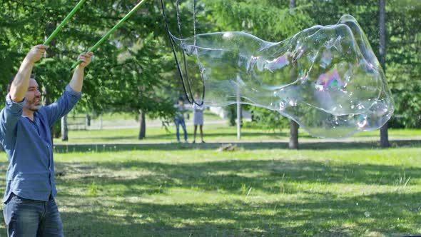 Little Boys Catching Huge Soap Bubble Made by Performer