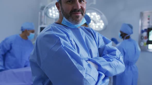 Portrait of caucasian male surgeon standing in operating theatre smiling to camera