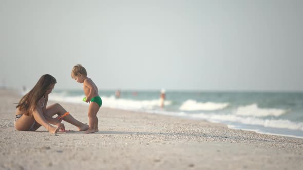 Older Sister Playing with Younger Brother Aground Near the Shore on Summer Vacation