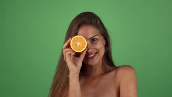 Studio Shot of a Gorgeous Happy Woman Smiling Holding Half of an Orange