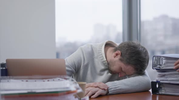 Exhausted Overwhelmed Man Sleeping on Table in Office As Woman Bringing Folders with Documents and