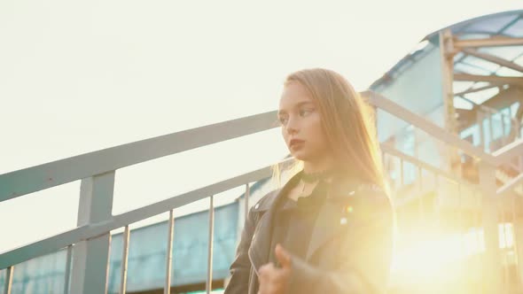 Rock Girl in Black Leather Jacket Walking Down Stairs on Golden Sunlight Background