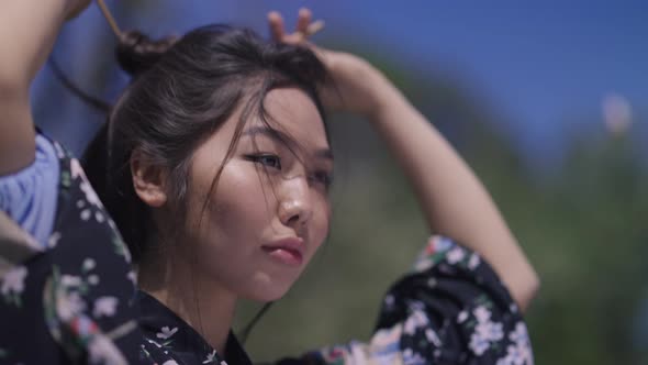 Closeup Portrait of Asian Gorgeous Woman Unbinding Buntail Shaking Long Black Hair in Sunlight