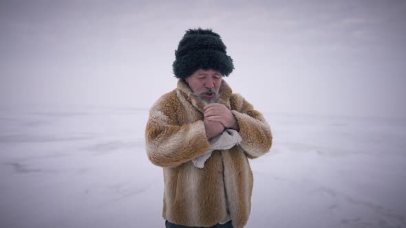 Medium Shot Old Man Taking Off Mittens Blowing on Frozen Hands in Slow Motion Standing on Frozen