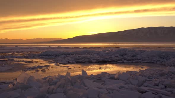 Panning over broken ice layers on Utah Lake during sunset