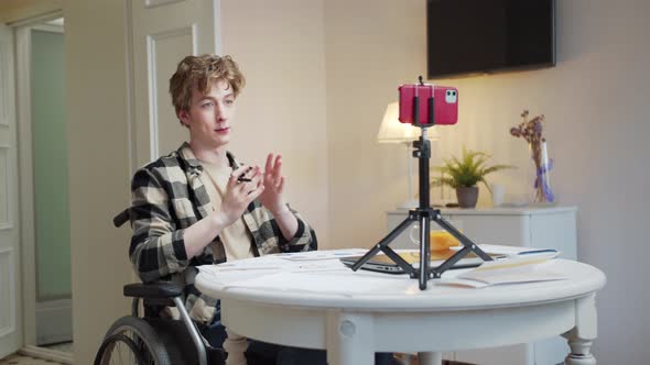 A Disabled Young Man is Talking with Someone and Showing Diagrams