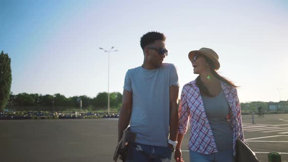 Young Attractive Mixed Race Couple Riding Skateboards and Having Fun Slow Motion