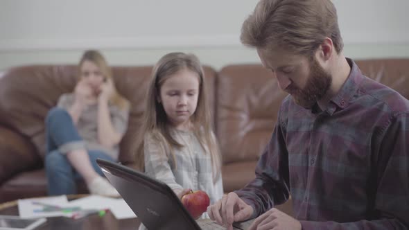 Portrait of the Bearded Man Working with Tablet Close Up. Little Girl Unsuccessfully Trying To Give