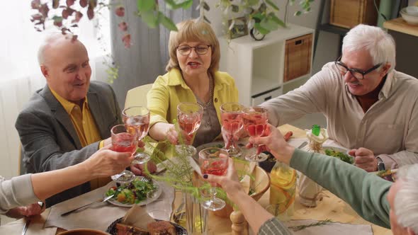 Senior Friends Clinking Drinks in Toast at Dinner